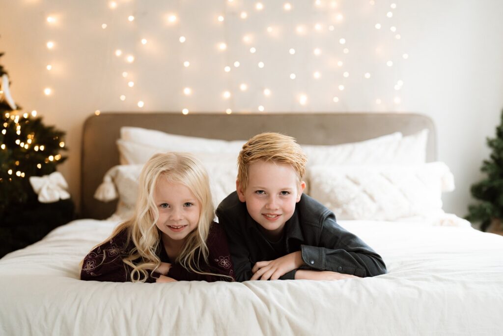 Kerst shoot in Gouda waar broer en zus samen poseren in kerstsfeer op bed.