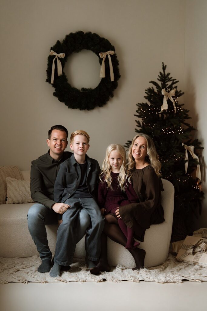 Een familie die samen poseert op de bank tijdens een minishoot voor de kerst.